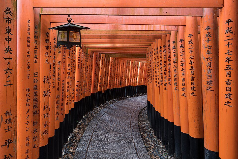 A lantern lights the torii-lined path at Fushimi Inari.